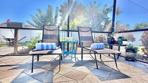 Un'area esterna coperta con piscina, lettini e piante in vaso.