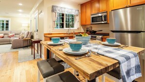 A modern kitchen with wooden cabinets, stainless steel appliances, and a dining area with a wooden table and chairs.