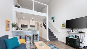 A modern apartment with a living room, kitchen, and dining area. It features a sofa, coffee table, and a TV.