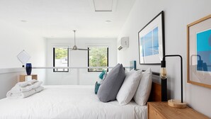 Camera moderna con un letto grande, un comodino in legno, una ventola a soffitto e una finestra vista verde.