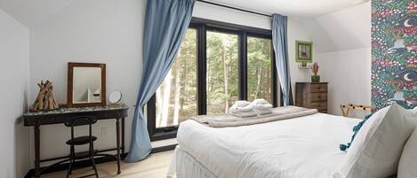 Un dormitorio con una cama grande, un escritorio con silla, una ventana con cortinas y un tapiz en la pared.