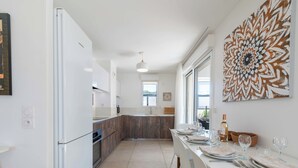 A modern kitchen with white cabinets, a wooden island, and a dining area with a table set for four.