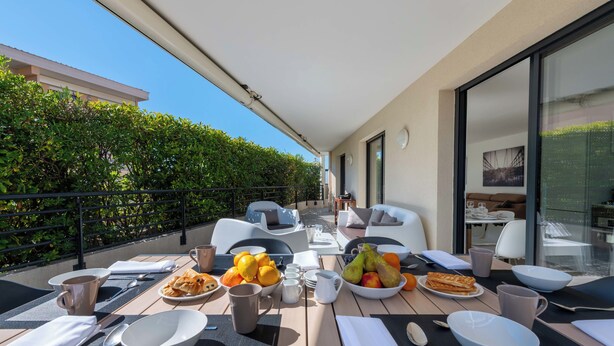 An outdoor dining area with a table set for breakfast, including fruits, pastries, and beverages.