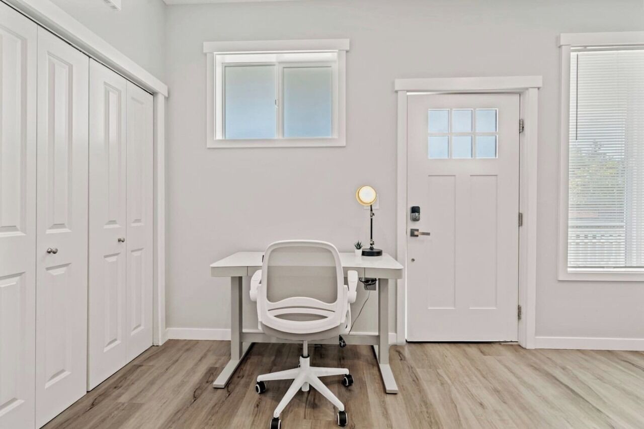 Ein Zimmer mit Schreibtisch, Stuhl und einer Tür mit Fenster.