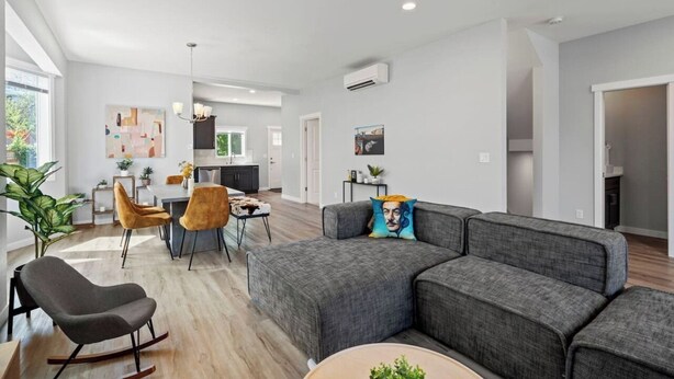 Uma sala de estar moderna com um sofá seccional, um espaço de refeições e uma cozinha ao fundo.