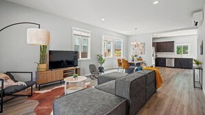 Uma sala de estar moderna com sofá, TV e área de jantar.