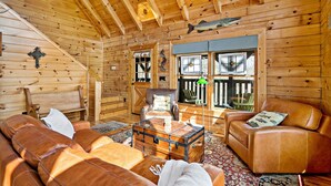 A log cabin interior with a leather sofa, a leather armchair, a glass coffee table, and a wooden ceiling. - Nice Views, Log Cabin, Gated Community - Mountain Vista by Carolina Properties (Bostic)