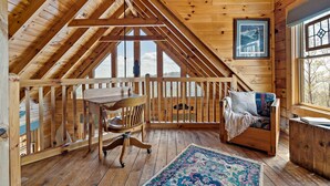A wooden cabin interior with a dining table, a cushioned seating area, and a large window. - Nice Views, Log Cabin, Gated Community - Mountain Vista by Carolina Properties (Bostic)