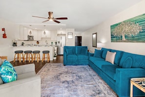 A modern living room with a blue sofa, a coffee table, and a patterned rug. - Recently updated spacious 1bd in Maui (Kihei)