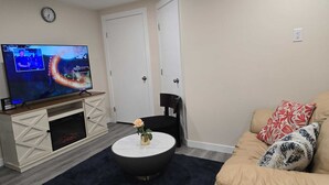 Una sala de estar con televisor, mesa de centro, sofá y una puerta.