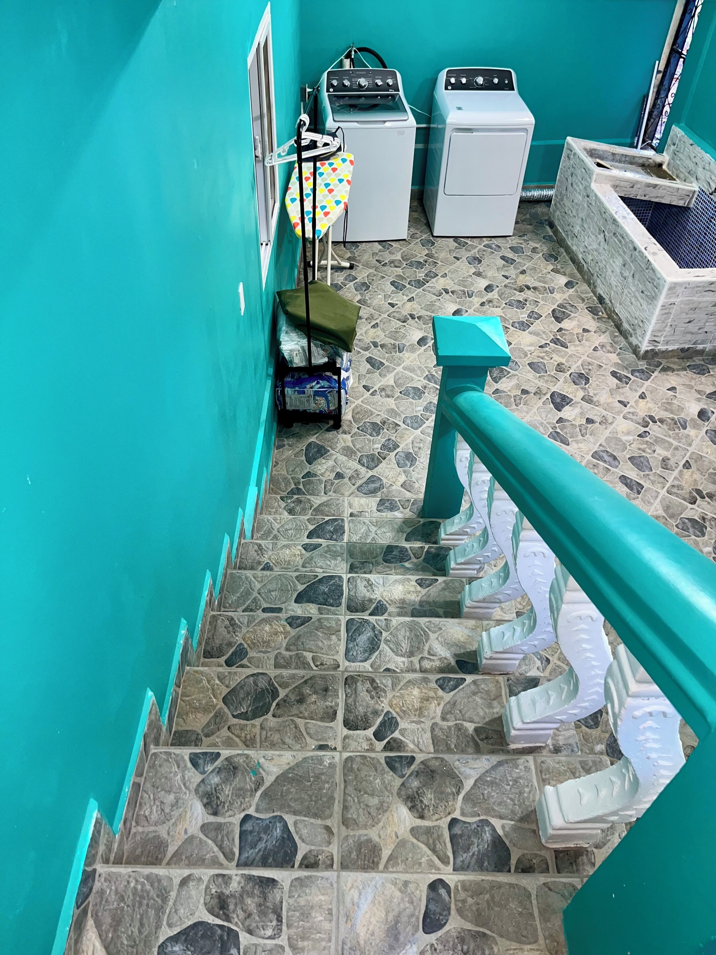 Zona de lavandería con dos lavadoras, un tendedero y piso de baldosas.