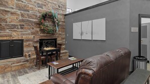A stone fireplace, a leather couch, a coffee table, and a wall with three framed pictures. - Carriage House 101 | Kitchenette | Near Dining & Shopping | Hot Tub | Pool (Park City)