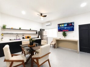 Eine moderne Küche mit Essbereich, einem an der Wand montierten Fernseher und einem Deckenventilator.