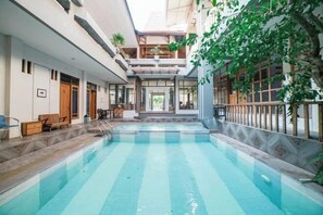 Ein Hallenbad mit Blick ins Gebäudeinnere, einschließlich Treppe und Sitzbereich.