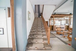 A staircase leading to a dining area with a wooden railing and patterned floor tiles. - Blok O International Guest House by MHM (Banguntapan)