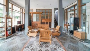 A spacious room with a large wooden dining table, comfortable seating, and a patterned floor. - Blok O International Guest House by MHM (Banguntapan)