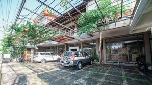 A courtyard with a car parked in the center, surrounded by potted plants and a glass ceiling structure. - Blok O International Guest House by MHM (Banguntapan)