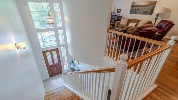 A staircase with white railings and wooden steps leading to a living area with a brown leather sofa and a red chair. - Cozy Townhouse near Midtown (Houston)