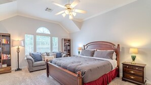 A bedroom with a large bed, a ceiling fan, a sofa, a nightstand, and a bookshelf. - Cozy Townhouse near Midtown (Houston)