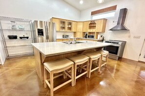 A kitchen with a large island, stainless steel appliances, wooden cabinets, and a built-in oven.