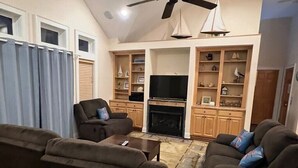 A living room with a fireplace, television, and built-in shelves with decorative items.