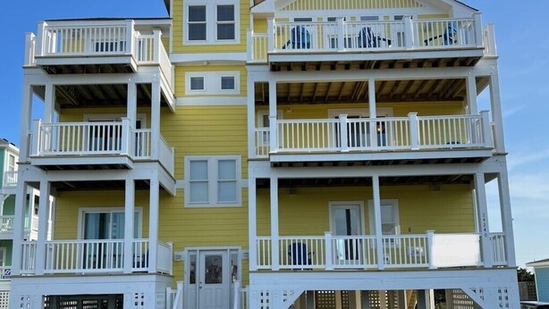 A multi-story building with balconies and a yellow facade.