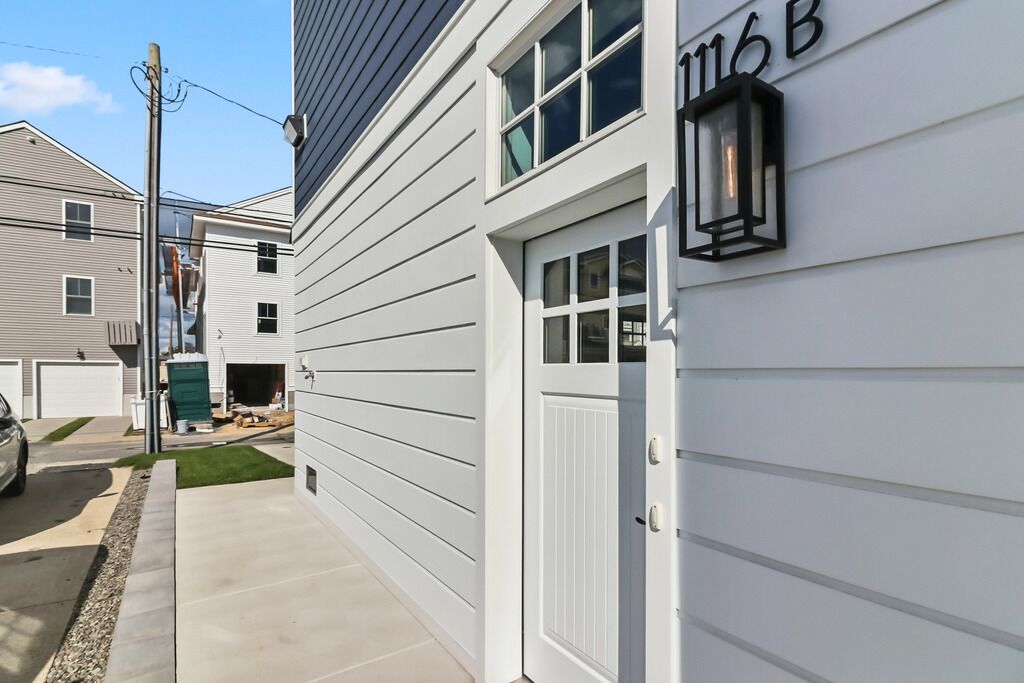 A residential building with a white exterior, a garage door, and a mailbox.