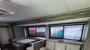 Un intérieur de camping-car compact comprenant un coin cuisine, un espace salon avec des sièges rembourrés et de grandes fenêtres.