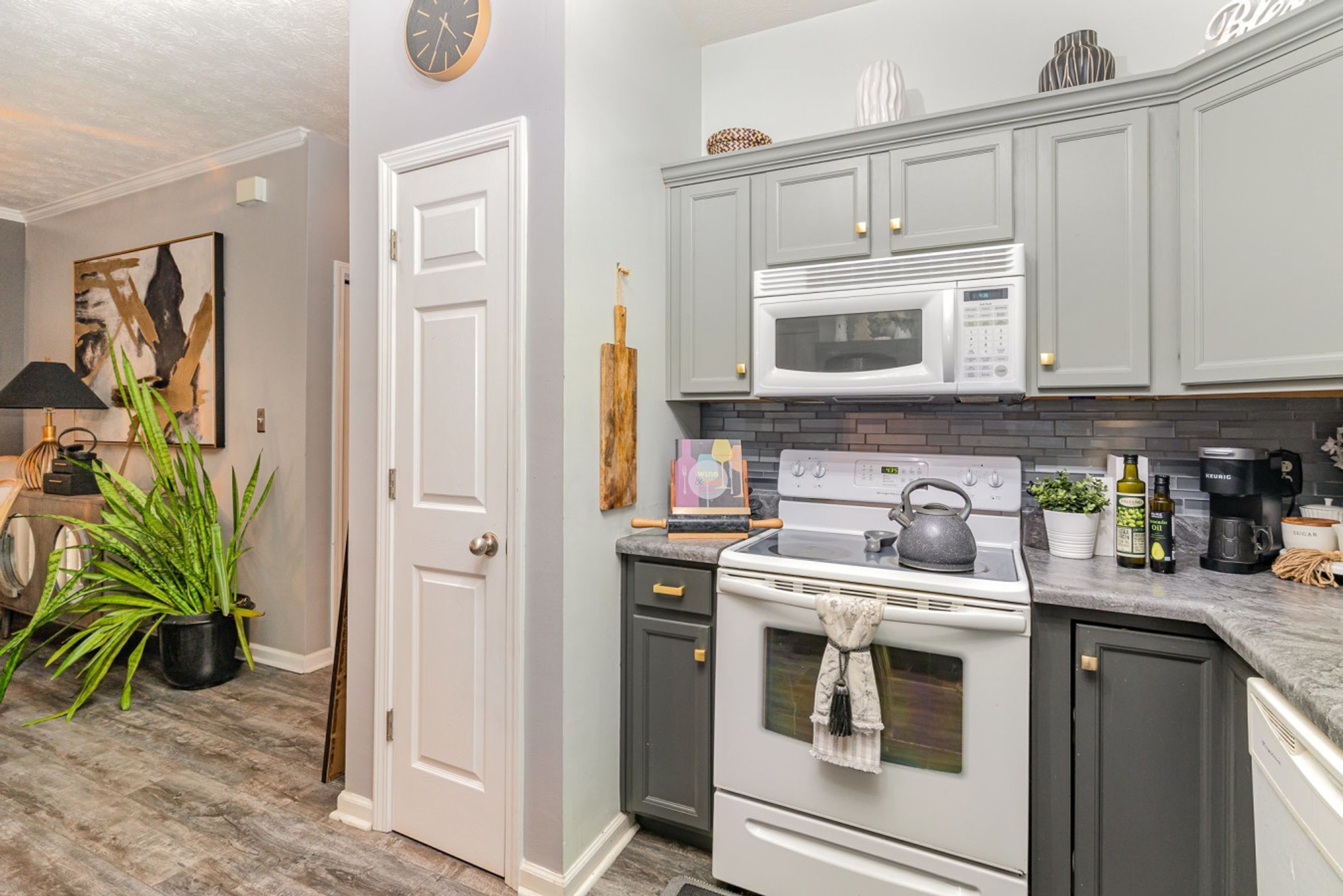 A kitchen with grey cabinets, a white stove, a microwave, and a coffee maker.