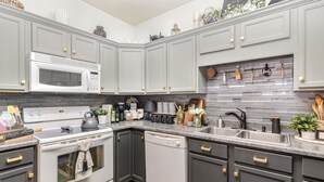A modern kitchen with grey cabinets, a white microwave, and a built-in oven.
