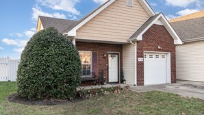 A single-story house with a brick facade, a white garage door, and a well-maintained lawn.