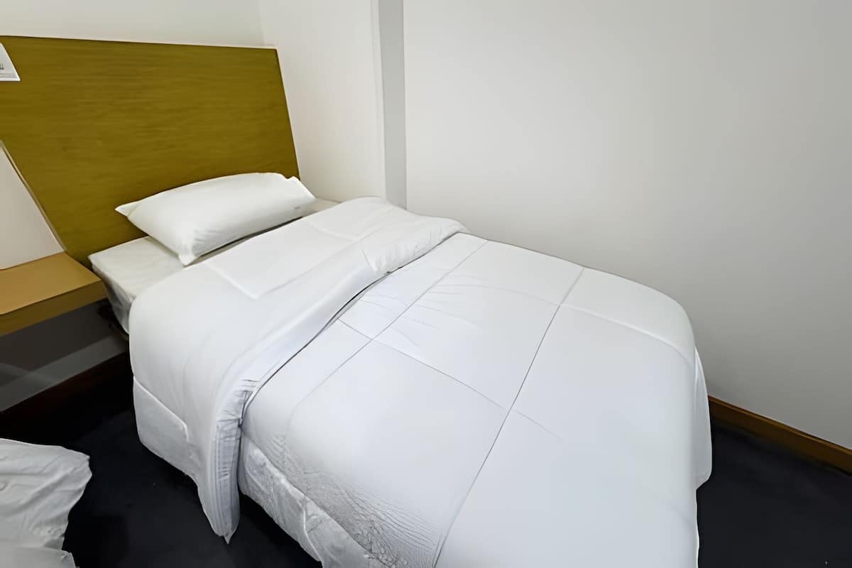 Una cama bien hecha con ropa blanca en una habitación de hotel.