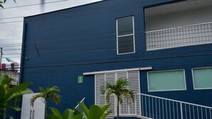 Un edifici blau amb un balcó, una escala i plantes en testos.