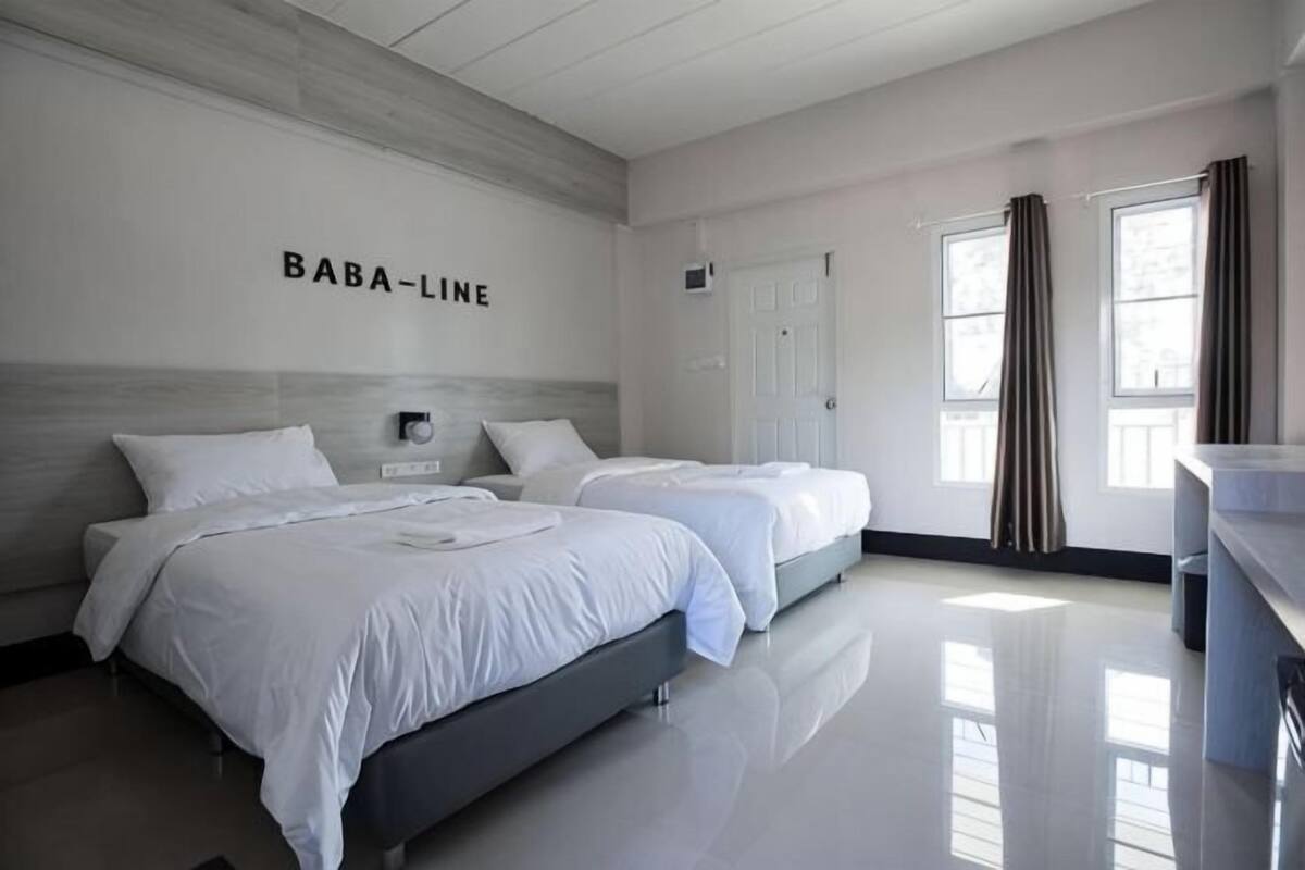 A hotel room with two beds, a minibar, a bathroom, and a view of the outside.