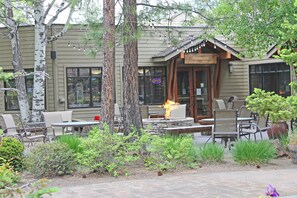 An outdoor seating area with tables and chairs, surrounded by trees and plants. - 7th Mtn 923B - Three Bedroom Condo (Bend)