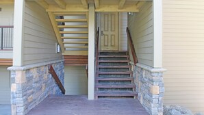 Una escalera con paredes de piedra y escalones de madera que lleva a una puerta.
