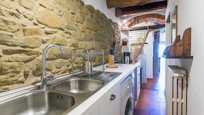 A kitchen with a stone wall, a wooden ceiling, and a washing machine.