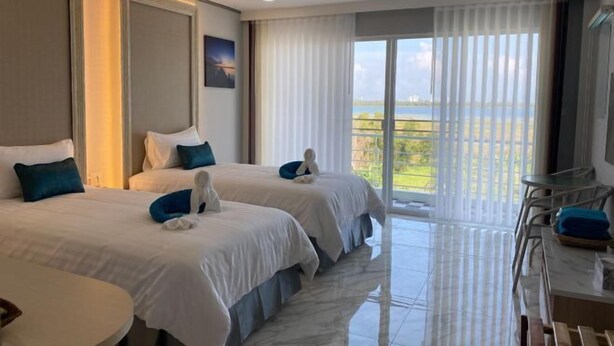 Een hotelkamer met twee bedden, een balkon met uitzicht en een zithoek met stoelen.