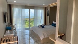 Een hotelkamer met een groot bed, een bureau, een stoel en een balkon met uitzicht.