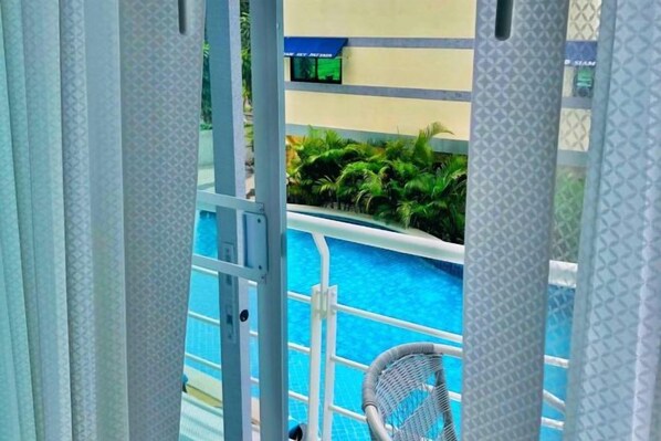 A pool area with a chair and a railing, surrounded by greenery. - Siam Sky Pattaya Hotel (Bang Lamung)