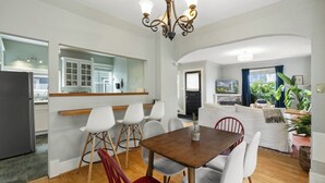 Een moderne keuken met witte kasten, een eethoek met een houten tafel en stoelen, en een woonkamer met een bank en een televisie.