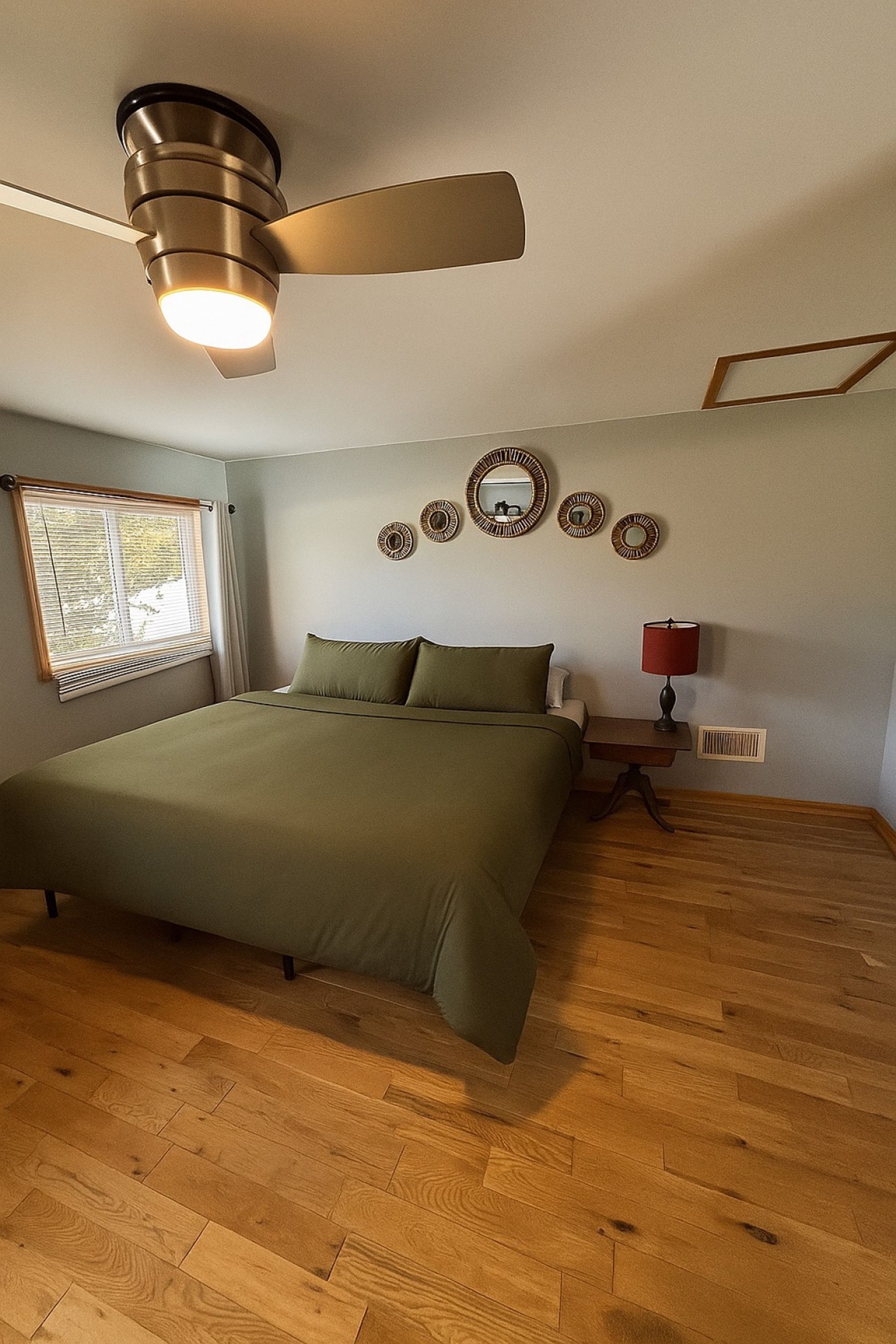 A bedroom with a bed, a ceiling fan, a window with blinds, and wall decorations.
