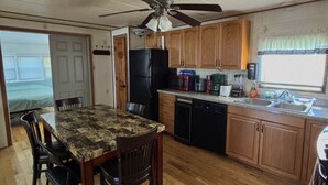 Una cocina con armarios de madera, un refrigerador negro, un microondas y una cafetera.