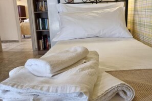 A neatly made bed with white linens and a rolled-up towel on the side. - Happy Home Piramide Cestia Lussuoso Unico Esclusivo a Roma (Rome)