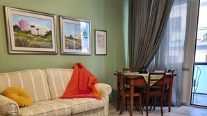 A living room with a sofa, a dining table with chairs, and two framed pictures on the wall. - Happy Home Piramide Cestia Lussuoso Unico Esclusivo a Roma (Rome)