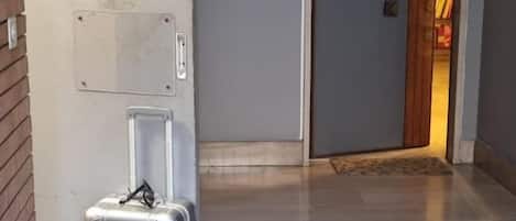 A hallway with a suitcase, a door, and a wooden floor.
