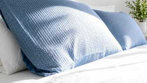 A bed with white bedding and blue pillows. - Canopy House - Brand New Home in Nature’s Arms (Greenbank)