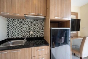 A kitchen with wooden cabinets, a black countertop, a tiled backsplash, and a built-in refrigerator. - New Nordic Trend 4 by Apartwell (Pattaya)