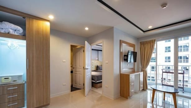 A modern hotel room with a bed, a desk, a TV, and a balcony with a view. - New Nordic Trend 4 by Apartwell (Pattaya)