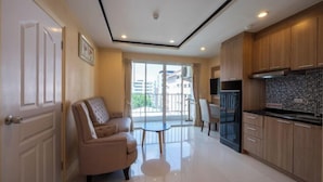 A modern kitchen with wooden cabinets, a black refrigerator, and a dining area with a table and chairs. - New Nordic Trend 4 by Apartwell (Pattaya)
